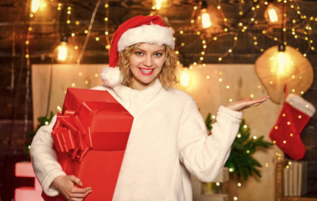 Buy lots of gift wrappers. New year. If you have lot of gifts to wrap then turn it into gift wrapping party. She deserves all best. Girl santa hat hold wrapped gift box. Ribbons bows accessoriesの写真素材