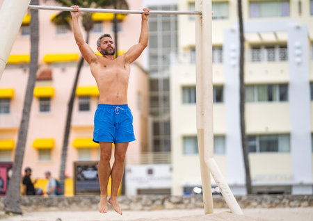 Man pullup. Muscular man sportsman with strong torso muscle. Sport pullup workout. Sport training. Man sportsman do pulling exercise. Man muscular athlete doing pull up in outdoor gym, copy spaceの写真素材