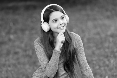 Teen girl listen music in wireless headphones. Gen z lifestyle. Style of music. Stylish teen girl listen music. School student lifestyle. Listen audio. Music lifestyle. Pondering girl outdoorの写真素材
