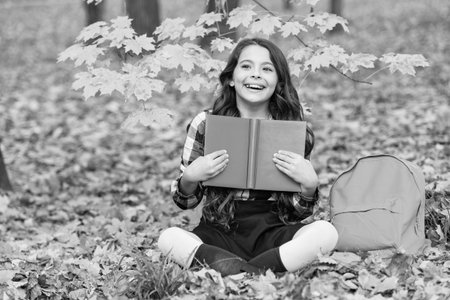 School education. School girl reading book outdoor. Teen girl reading in the autumn park. Education and knowledge. Knowledge day. Self education. Autumn book. Back to school. Happy childhoodの写真素材