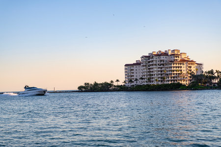 Miami architecture and motorboat, Florida. Luxury yacht boat at Fisher island. Summer vacation. Fisher island residential building and luxury yacht boat. Motorboat passing Fisher island, Miamiの写真素材