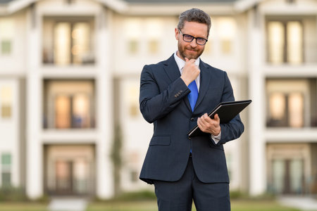 Realtor in suit. Rent or buy new home. Home insure. Property insurance promotion. Successful broker. Mortgage insurer. American sales manager. Real estate agent at house for sale. Skilled negotiatorの写真素材