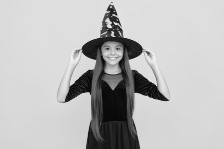 Teen girl in witch costume. Happy Halloween. Girl witch in Halloween costume isolated on yellow. Trick or treat. Celebrate All Hallows party holiday. All Hallows. October 31. Spooky seasonの写真素材