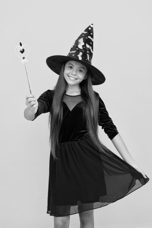 All Hallows party. All Hallows witch. October 31. Teen girl in witch costume hold magic wand. Happy Halloween. Girl witch in Halloween costume isolated on yellow. Trick or treat. Costume partyの写真素材