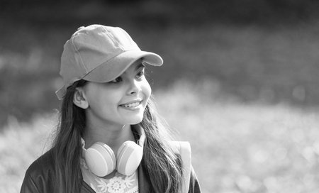 Listen audio. Music lifestyle. Teen girl listen music in headphones outdoor. Gen z lifestyle. Style of music. Stylish teen girl listen music. School student lifestyle. Copy space advertisementの写真素材