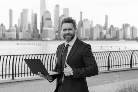 Businessman freelancing in New York. Business man working online. Businessman busy working on laptop or computer outdoor. Man send business email and surf on a web browser. Thumb upの写真素材