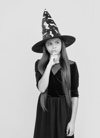 All Hallows. October 31. Pondering teen girl in witch costume. Happy Halloween. Girl witch in Halloween costume isolated on yellow. Trick or treat. Celebrate All Hallows party holidayの写真素材