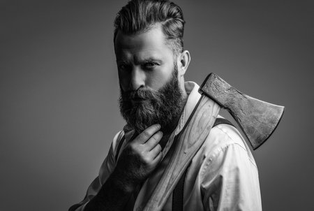 Hair and beard care. Handsome bearded brutal man. Beard styling. Brutal Caucasian hipster with moustache. Bearded man isolated on grey. Bearded man hold ax. Classic charmの写真素材