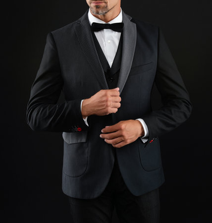 Rich businessman on formal event. Man in rich bespoke tux. Tuxedo man in menswear isolated on black. Successful man in formal menswear, cropped view. Menswear fashion. Elegant tuxedo bowtieの写真素材