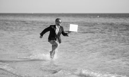 successful businessman in suit has business success run in sea at summer vacationの写真素材