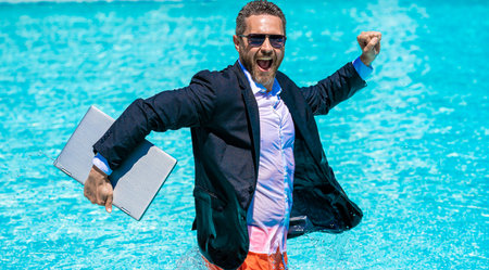 Businessman in suit with laptop at swimming pool. Happy freelancer. Business trip success. Business...