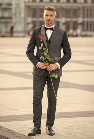 elegant man in black tux. man wearing tux bowtie outdoor. tux man with red rose. full length.の写真素材