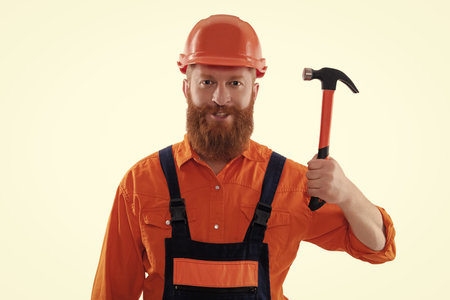 Surface repair. Carpentry and repairing. Repairman in uniform has hammer. Bearded repairman with hammer. Workman repairing with hammer isolated on white. Repair man work. Home repair and improvementの写真素材