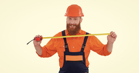 Man builder worker. Builder isolated white. Man builder engineer. Architect measuring size. Tape measure. Civil engineer man. Architect worker man hold measuring tape. Detailed site measurementsの写真素材