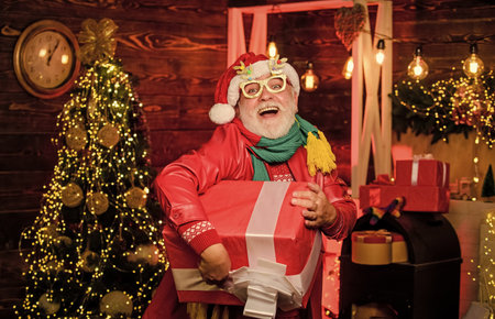 December sale. Christmas gift. Presents for family. Surprise concept. Santa Claus delivering gift. Delivery service. Gift shop. Man senior Santa claus hold gift box. Winter ideas. Celebrate new yearの写真素材