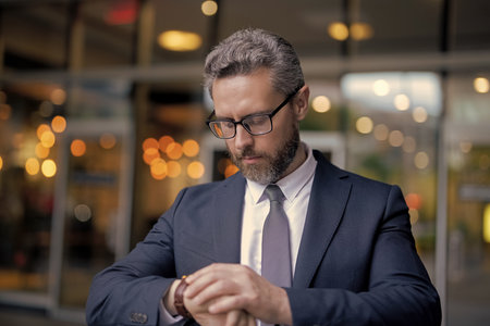 Business deadline. Businessman late for business deadline. Time management. Punctual man check time on watch being late. Businessman with watch. Punctual businessman checking time outdoor. Copy spaceの写真素材