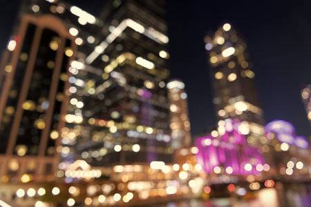 Defocused cityscape. Blur backdrop. City at night defocused background. Defocused blur illuminated city architecture. Blurred illuminated skyscraper. Blurred background of night cityの写真素材