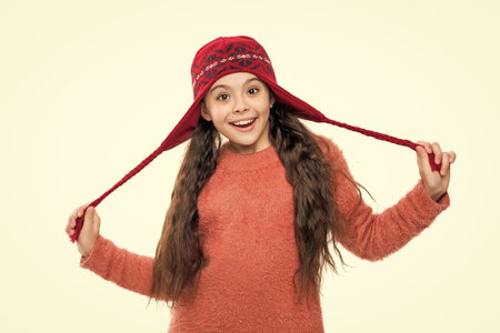 Teen girl wearing knitted sweater. Winter fashion style. Stylish girl in winter hat. Teen child portrait wearing warm winter hat. Girl kid isolated on white. Happy childhood. Trendy snow hatの写真素材