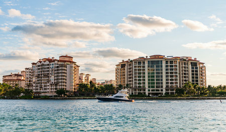 Yacht at Fisher island luxury residential building. Vacation on summer. Fisher island building. Luxury motor boat yacht. Yacht go to marina. Boating and yachting. Luxury lifestyleの写真素材