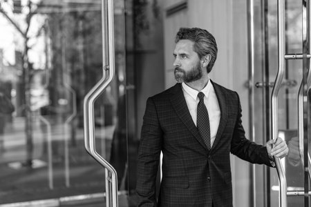 Mature entrepreneur at office door. American businessman suit leaving office building. CEO man entering business office. Business man. Successful businessman entering office. Successful businessmanの写真素材