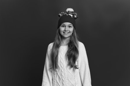 Teen girl in Christmas hat and knitted sweater for winter holiday season isolated on red studioの写真素材