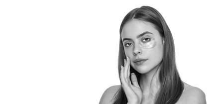 Young woman using patches under eyes, copy space. Beauty woman with eye patches has perfect skin. Collagen hydrogel eye patches. Skin with moisturizing patches under eyes. Combat dark circlesの写真素材