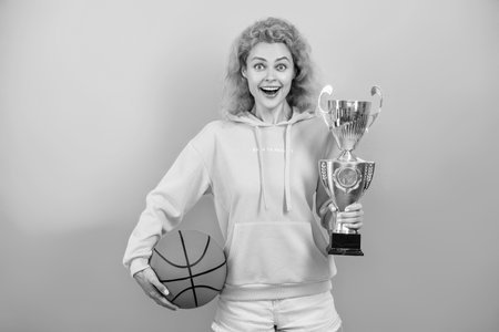 Woman won the prize. Celebrating success. Winning the game. Sport achievement award. Woman with basketball ball and champion cup. Happy girl basketball player. Sport success. Iconic championの写真素材