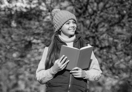cheerful teen kid read school book in autumnの写真素材