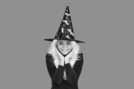 Girl witch in Halloween costume isolated on orange. Trick or treat. All Hallows costume party celebration. All Hallows witch. Girl in Halloween witch costume. Happy Halloween. Wide brimmedの写真素材