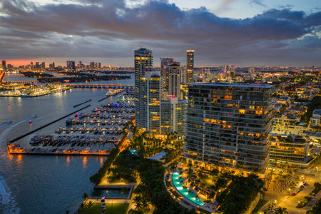 Twilight over Miami skyline and marina. Luxury yachts glowing in the Miami harbor. Sunset cruise near Miami downtown skyscrapers. Aerial night view of Miami Beach at dusk.の写真素材