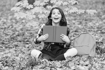 Back to school. School education. School girl reading book outdoor. Teen girl reading in the autumn...
