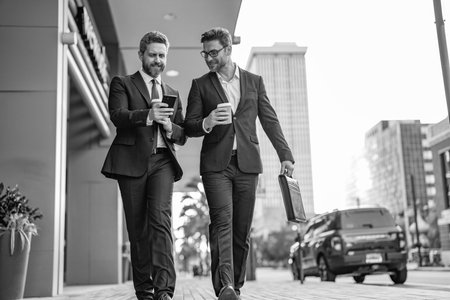 Success. Businessmen in suit walking outdoor. Two businessmen walking and talking in the city....