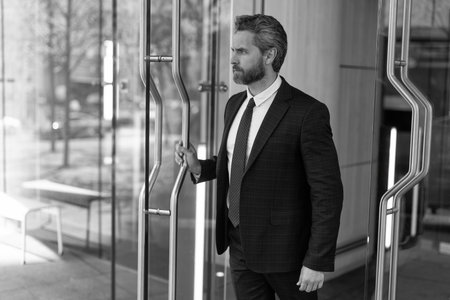 Successful businessman entering office. Adult entrepreneur at office door. Hispanic businessman in suit leaving office building. Boss man leaving business office. Business man. Startup businessの写真素材