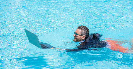 Freelance working online. Man using laptop for freelancing in swimming pool. Business freelancing. Businessman on summer vacation. Businessman having online meeting. Freelance man online video callの写真素材