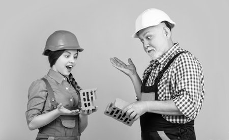 amazed child and granddad bricklayer in helmet