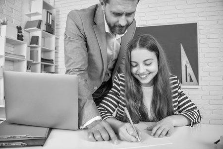 smiling child with tutor in classroom use laptop