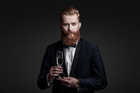 Elegant tuxedo man hold glass of champagne isolated on black. Celebrating success. Cheers. Bearded...