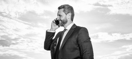 cheerful man has phone talk on sky background. man has phone talk outdoor.
