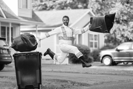Picking up garbage plastic for cleaning. Keeping garbage plastic into bag for trash. Pollution and recycling. Happy man putting garbage bag in a trash bin. Environmental protectionの写真素材