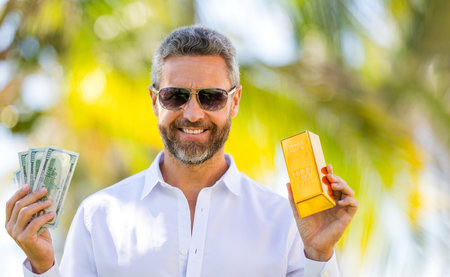 Rich businessman hold gold and cash money. Financial success. Successful rich man with gold and...