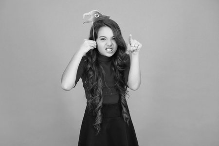 Trick or treat. All Hallows party celebration. All Hallows props. Funny party props. Girl with Halloween props. Happy Halloween. Girl ready for Halloween party isolated on orange. Pointing fingerの写真素材