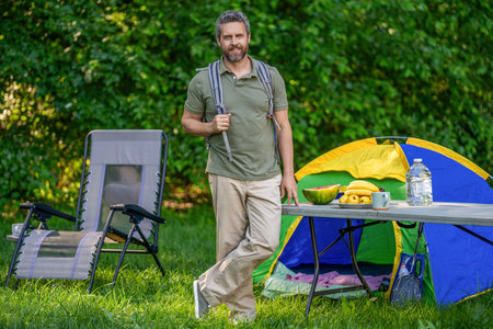 Picnic time. Man having camp picnic in forest with tent. Man hiking on summer day. Summer camp activity. Summer camping retreat. Camp adventure. Hiking lifestyle. Man at campsite. Hiking breakの写真素材