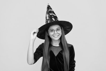 October 31. Teen girl in witch costume. Happy Halloween. Girl witch in Halloween costume isolated on yellow. Trick or treat. Celebrate All Hallows party holiday. All Hallowsの写真素材