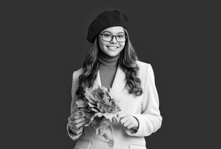 Autumnal season. Fall fashion. Happy young girl playfully hold yellow maple leaves. Teen girl with fallen leaves isolated on red. Autumn girl hold fallen leaves. Fall and autumn. Golden maple leavesの写真素材