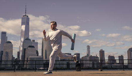Healthy lifestyle with daily fitness. Fitness and sport. Man running with energy. Sport lifestyle. Sportsman running with fitness mat. Sport man training outdoor in New York. Strength trainingの写真素材