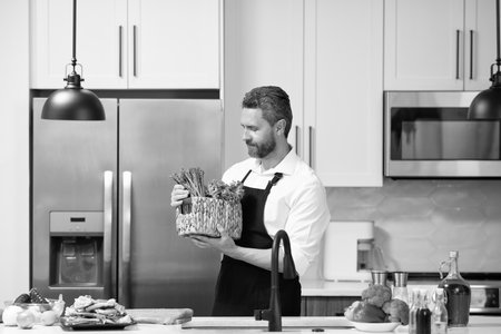 Hispanic man cooking home healthy food in apron choose ingredient for dinner menu in the kitchenの写真素材
