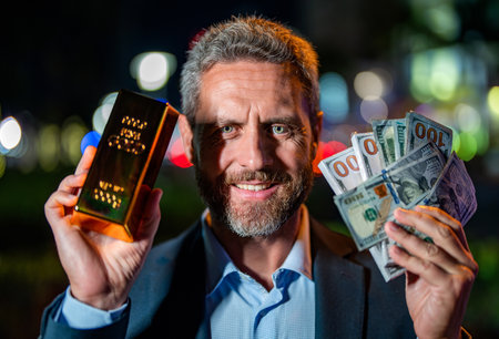 Successful rich man with gold and money. Business success man with gold bar. Golden bar. Golden bar and money. Rich businessman hold gold and money at night. Financial success. American dollar billsの写真素材