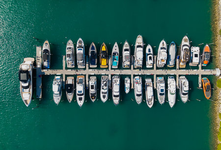 Aerial view of luxury yachts docked at marina. Top-down drone shot of yachts. Boats and sailboats line the scenic seashore.の写真素材