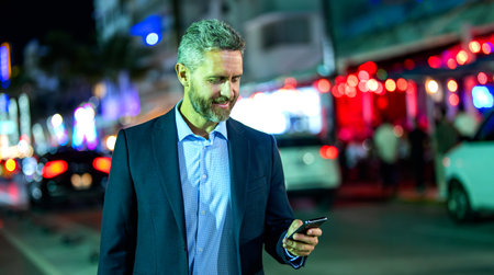 Businessman walking night city. Business man chat on phone outdoor. Businessman chatting on phone in night street. Businessman using smartphone. Successful businessman chatting online, bannerの写真素材