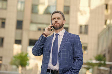 Social network. Hispanic business man with phone at office building. Businessman using phone. Man director phone conversation in city. Businessman talking on phone. Businessman in front officeの写真素材